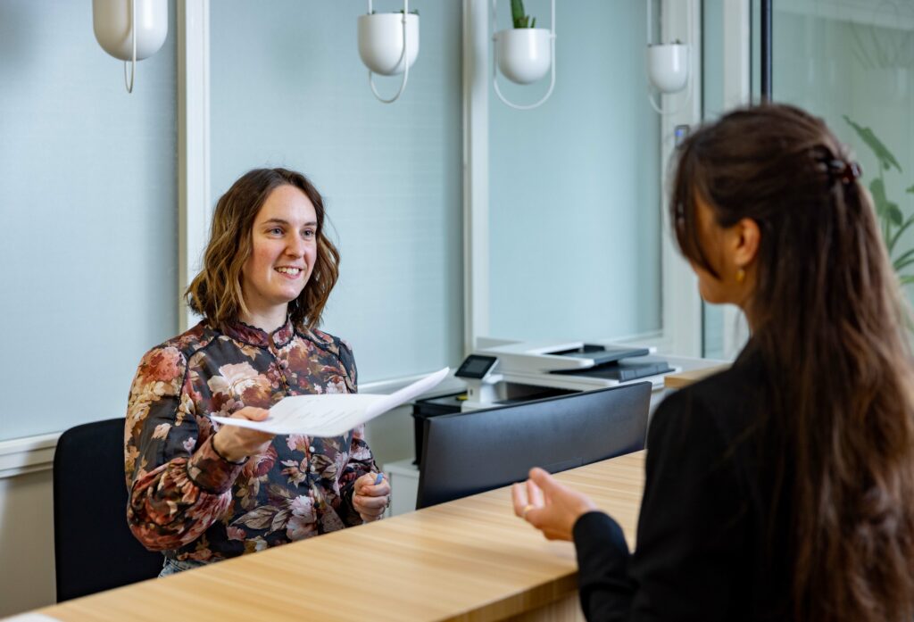 Biologische tandarts ontvangt patiënt aan de balie van het nieuwe holistisch centrum in Leeuwarden.